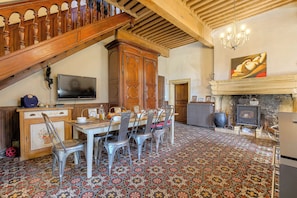 Un comedor con una escalera de madera, una chimenea y un televisor.