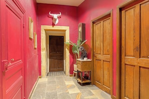 A hallway with red walls, a bull's head decoration, wooden doors, and a tiled floor.