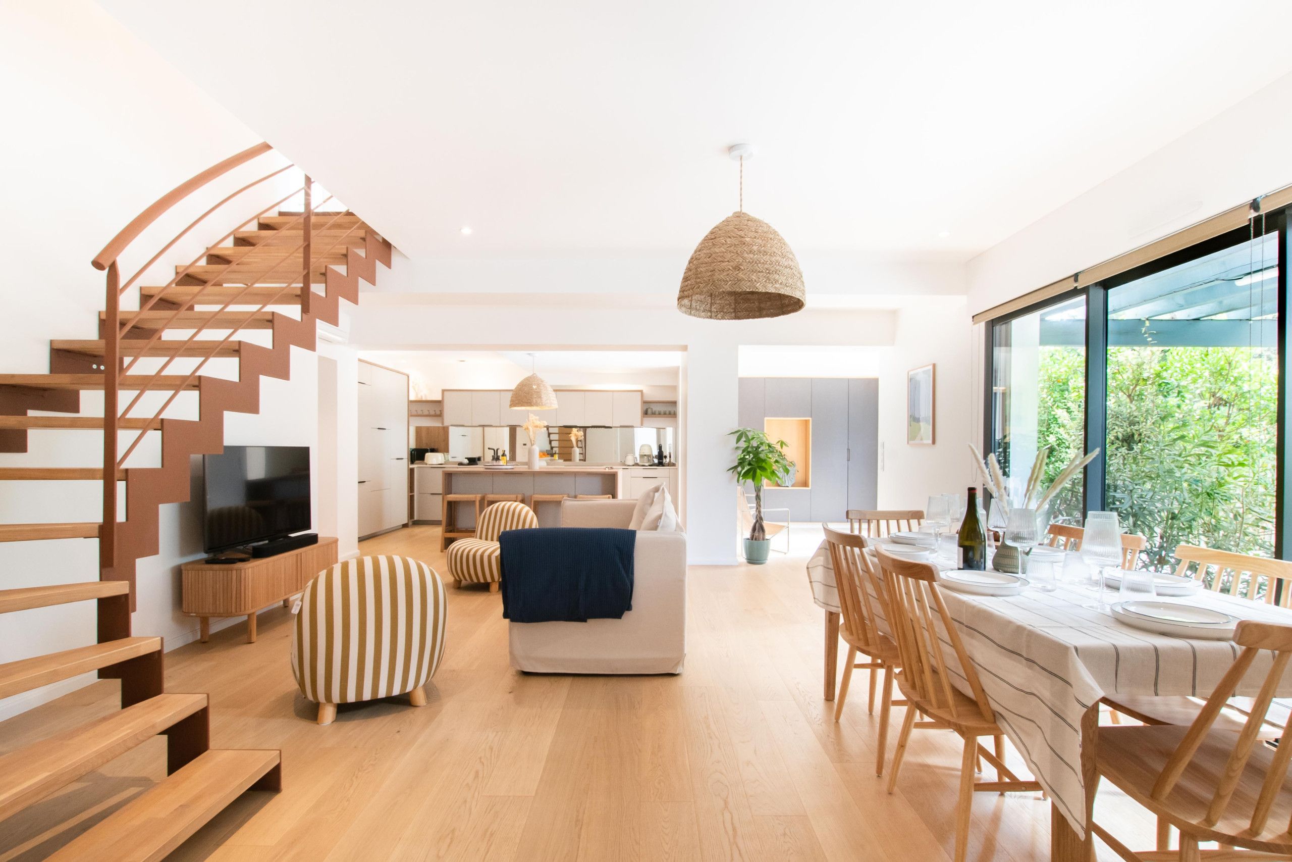 A modern living space with a spiral staircase, a dining area, and a kitchen.