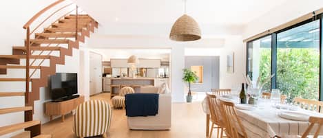 A modern living space with a spiral staircase, a dining area, and a kitchen.