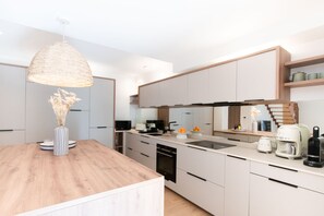 Ett modernt kök med en köksö i trä, inbyggda vitvaror och en hängande lampa.
