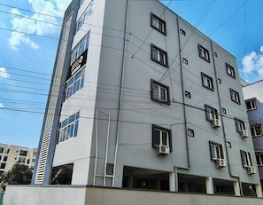 A multi-story hotel building with a modern design, featuring a prominent sign on the side. - Classic Srinivasa Home Stays (Hyderabad)