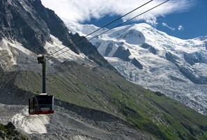A cable car with a mountainous backdrop, including a snow-capped peak and rocky terrain. - NEW! Apartment Alpage | Large Terrace (Les Houches)