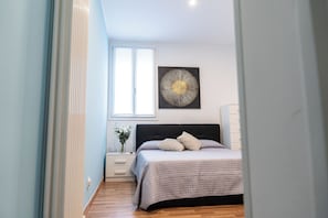 A bedroom with a bed, a nightstand, a vase with flowers, and a wall art piece. - Vrbo Property (Rovigo)