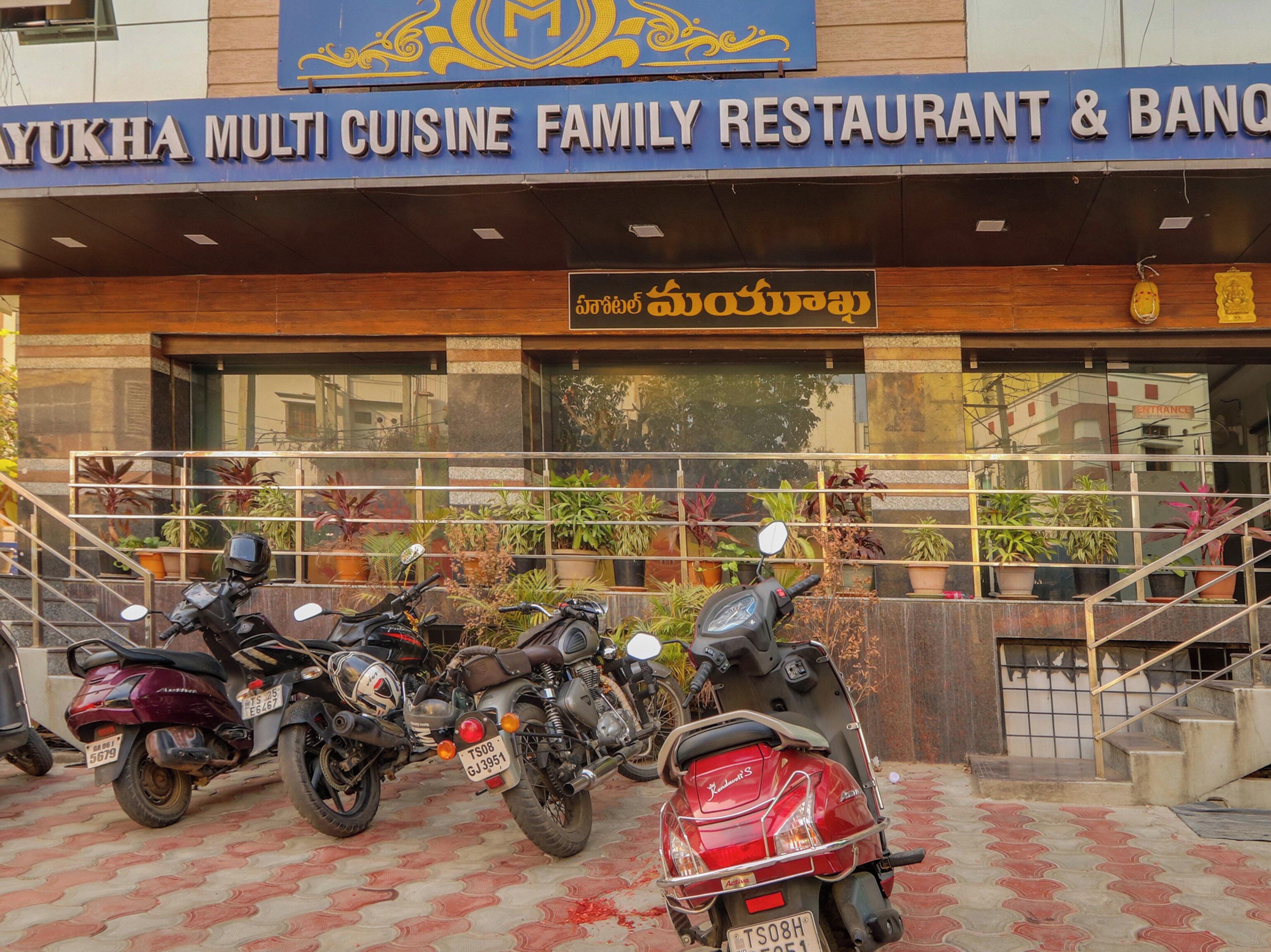 A family restaurant with a signboard and potted plants in front.