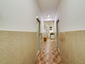 Un pasillo con suelo de cuadros, una recepción y una puerta al final.