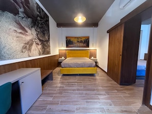 Une chambre à coucher comprenant un lit, des tables de chevet, un tableau accroché au mur et une armoire.