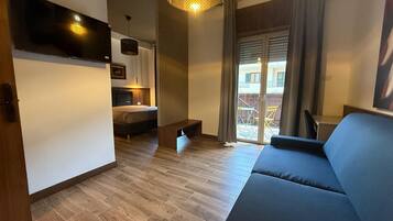 Ein modernes Wohnzimmer mit einer Couch, einem Bett und einem an der Wand befestigten Fernseher.