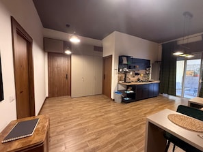 Un vaste espace de vie comprenant une cuisine, un plancher en bois et un placard à portes coulissantes.