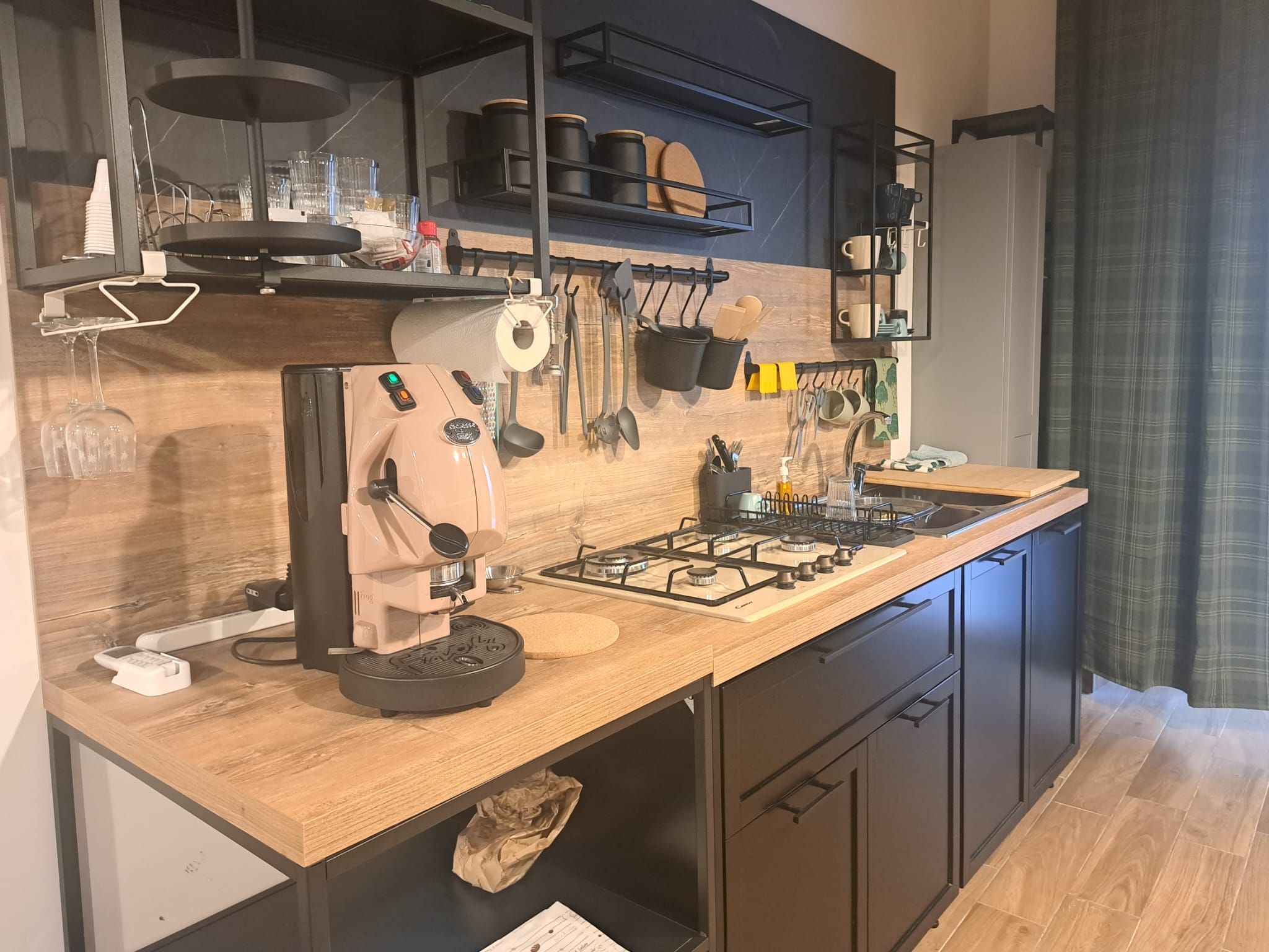 Eine moderne Küche mit einem eingebauten Gasherd, einer Kaffeemaschine und verschiedenen Küchenutensilien, die an der Wand hängen.