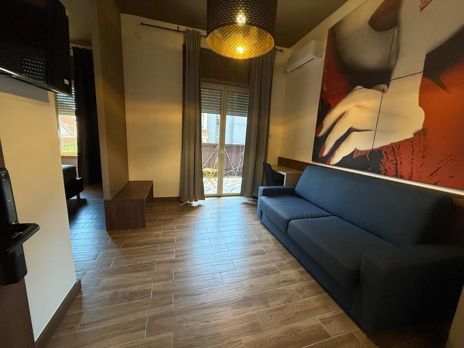 A modern living room with a sofa, a dining area with a table, and a large window with curtains.