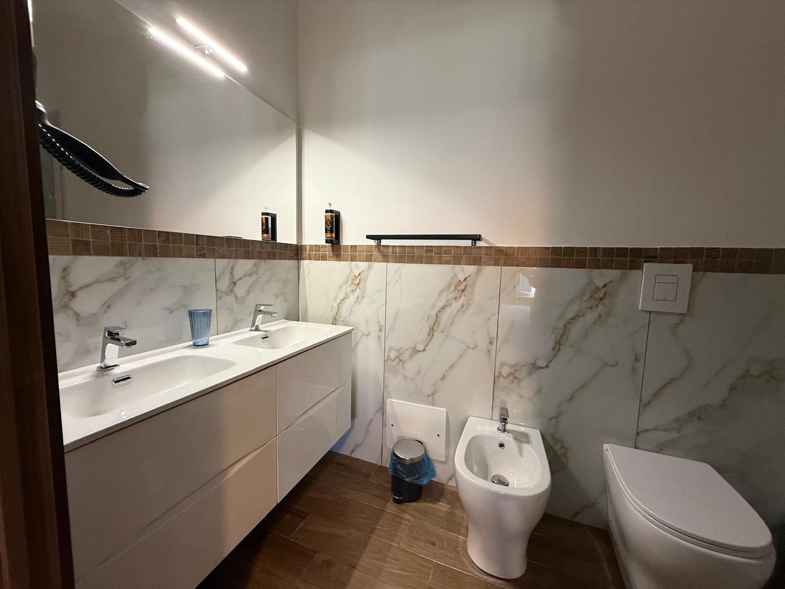 Un baño con lavamanos blanco, espejo e inodoro.
