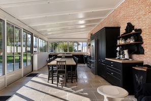A modern kitchen with a brick wall, large windows, and a dining area with a table and chairs. - Villa 'Demeure Marida' with Pool for Group of 15 (Moisy)