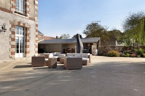A courtyard with outdoor furniture, a stone wall, and a building with a brick facade. - Villa 'Demeure Marida' with Pool for Group of 15 (Moisy)