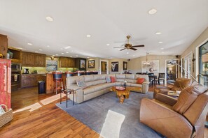 A spacious living area with a large sectional sofa, a coffee table, and a dining area with a chandelier. - Mountain Mischief - 4 Suites + Views + Hot Tub (Alto)