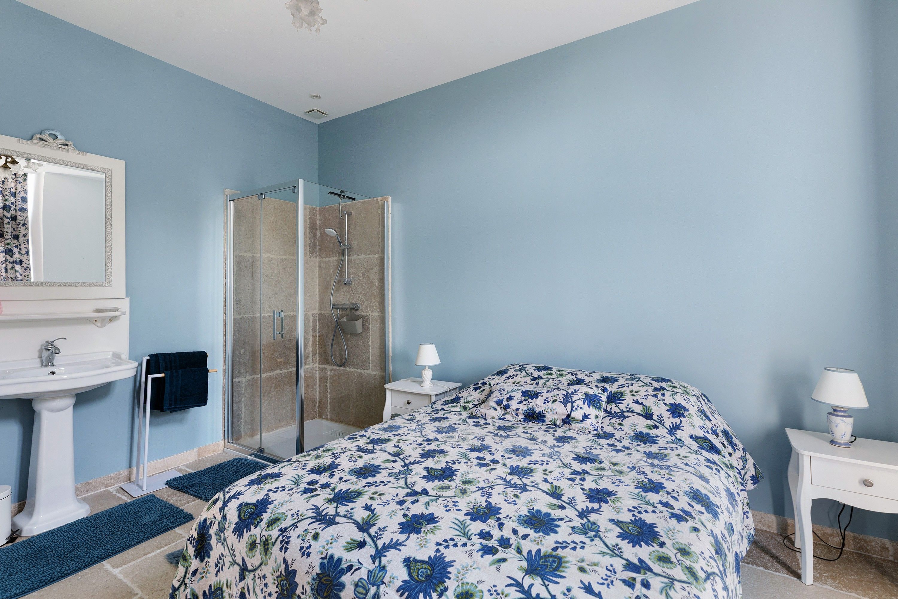 Ein Schlafzimmer mit einem Bett, einer Dusche, einem Waschbecken und einem Spiegel.
