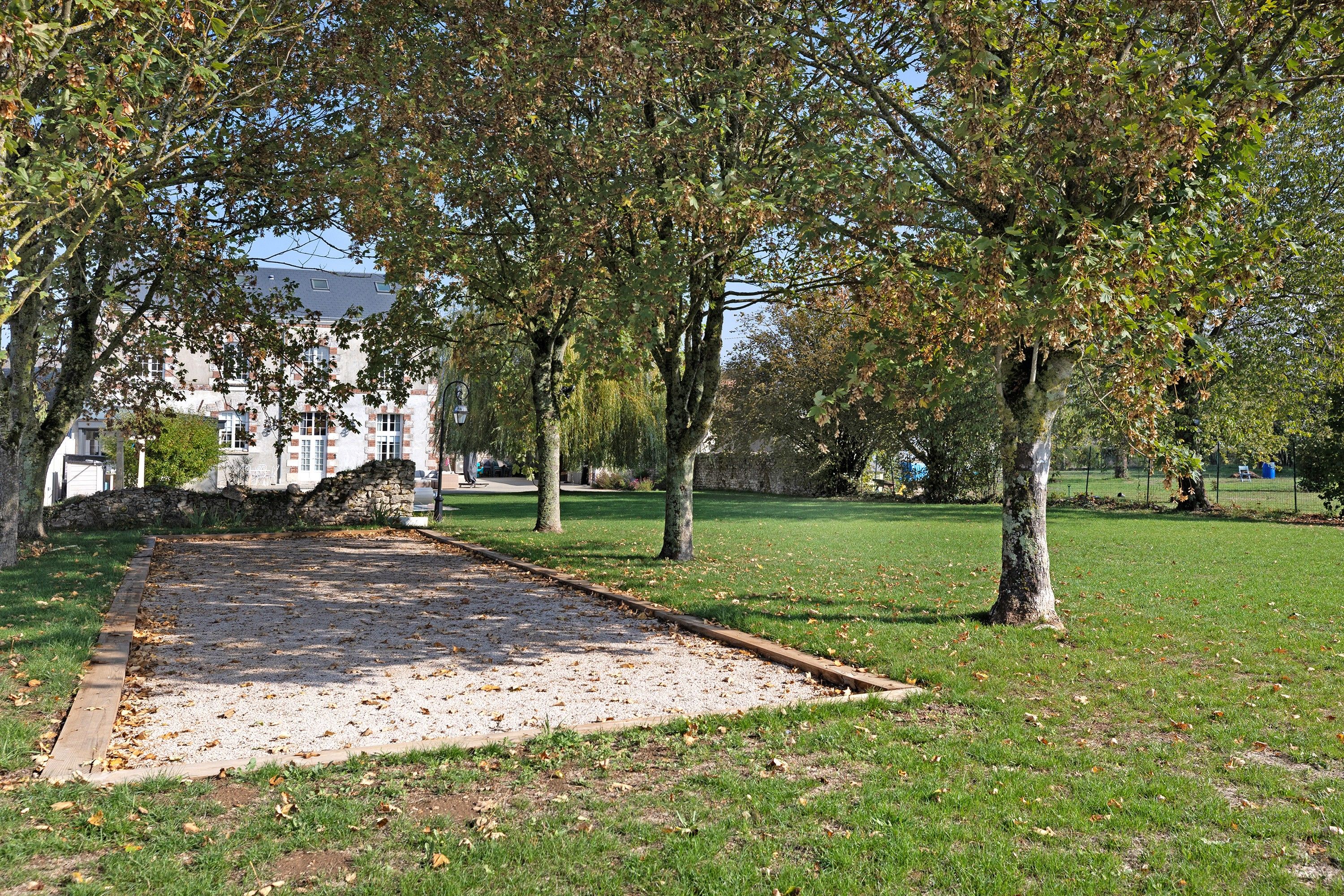 Een park met een grindpad, bomen en een gebouw op de achtergrond.