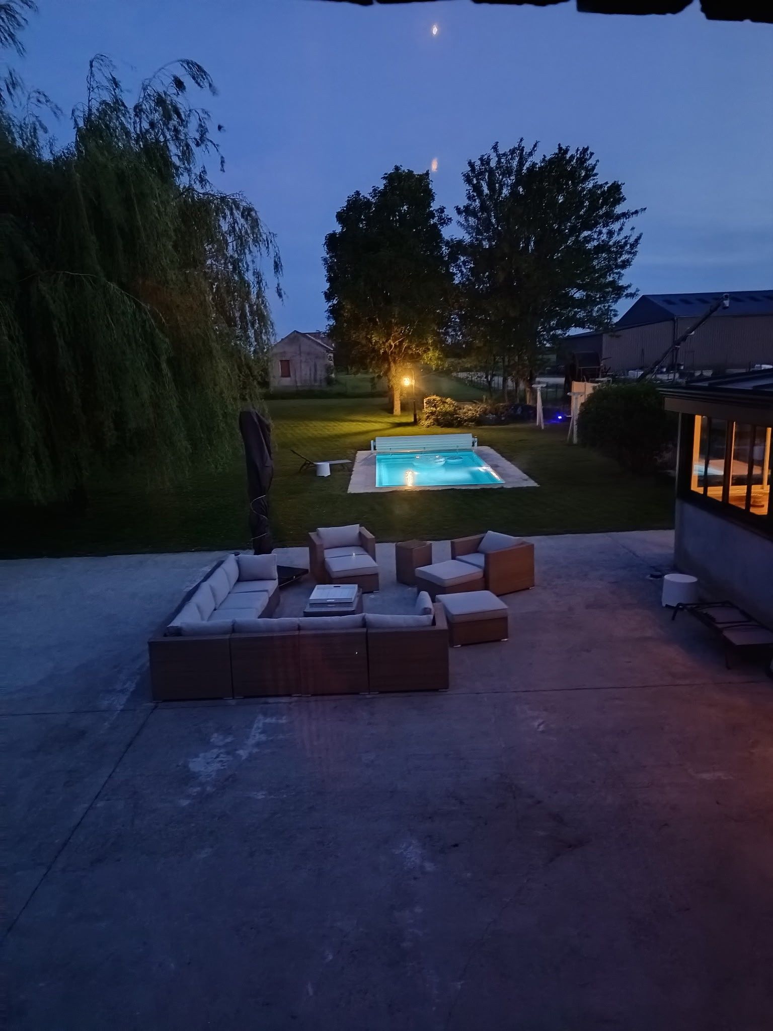 En trädgård med en pool, utomhusmöbler och ett hus i bakgrunden.