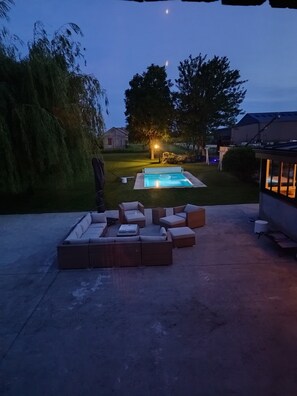 En trädgård med en pool, utomhusmöbler och ett hus i bakgrunden.