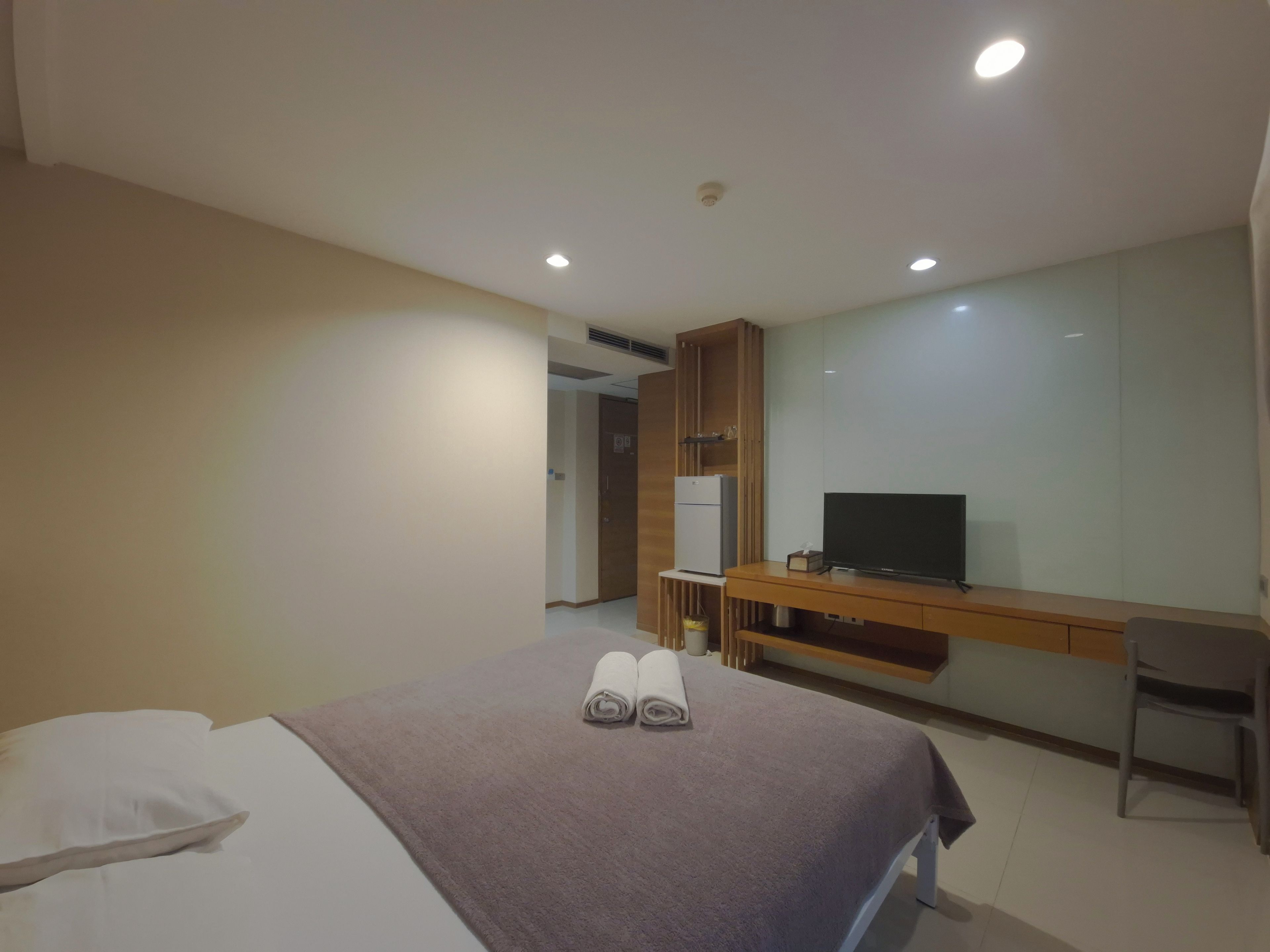 Una habitación de hotel con una cama, un escritorio con televisor y una silla.