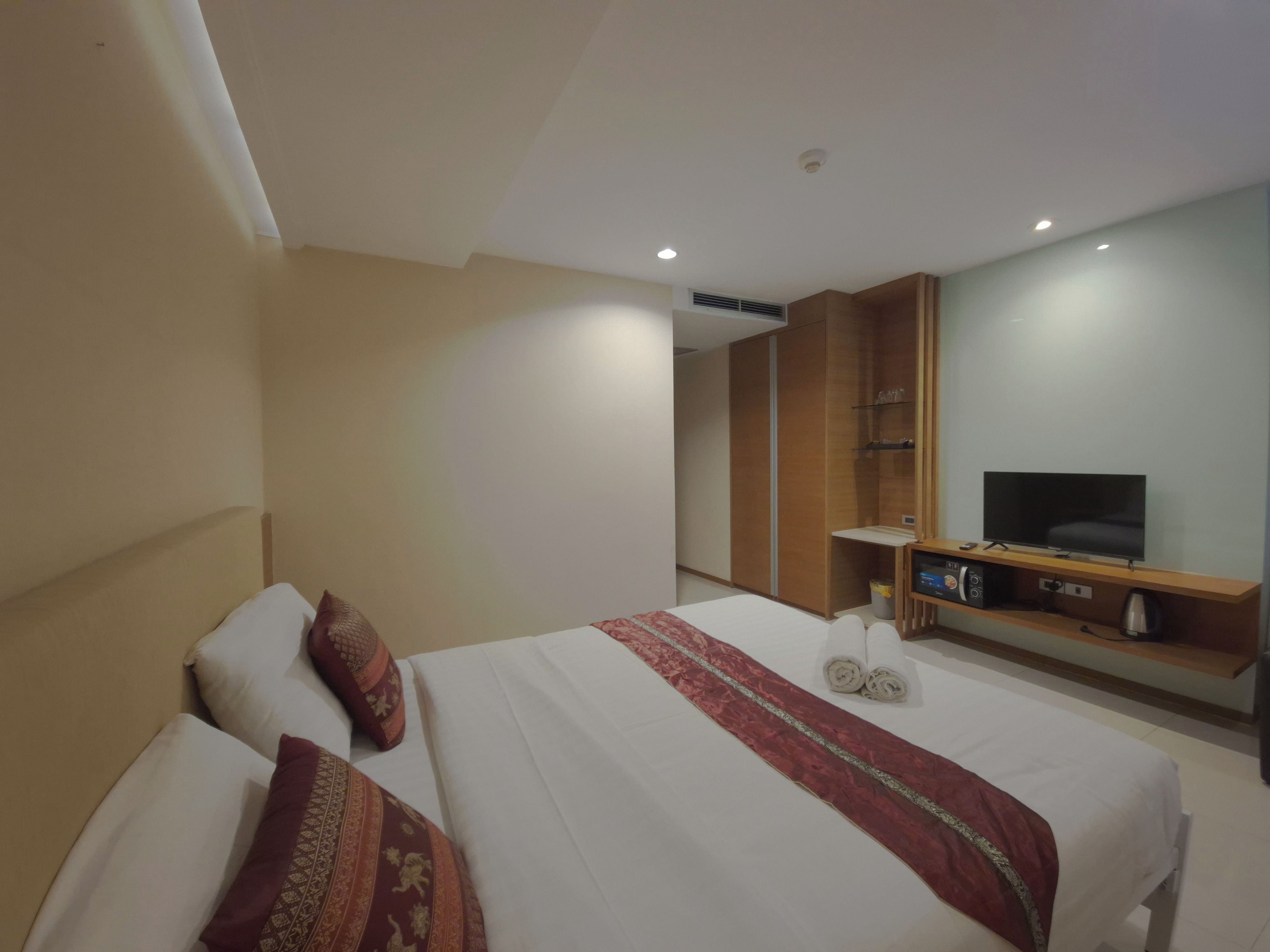Ett hotellrum med en säng, en tv, en minibar och en garderob.