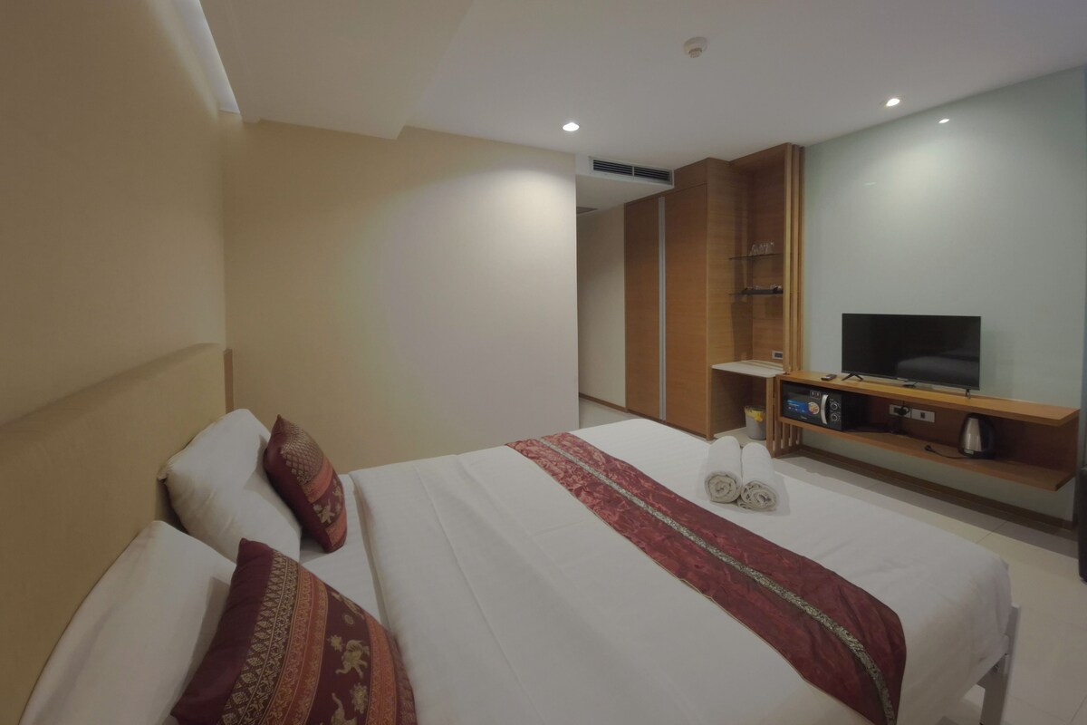 Ett hotellrum med en säng, en tv, en minibar och en garderob.
