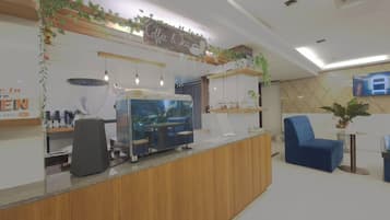 A reception area with a wooden counter, a coffee machine, and a seating area with a blue chair.