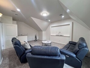 Ein großzügiger Loft mit hohen Decken, einer eingebauten Sitzecke mit Ledersofas, einem kleinen runden Tisch und Einbauleuchten.