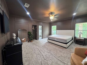 A bedroom with a bed, a desk, a chair, a plant, and a window. - 4-BD/4-BA Getaway w/ Cinema, Game Room & Backyard (DeSoto)