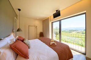 A hotel room with a large bed, a bedside table, a lamp, a chair, and a balcony with a view of the countryside. - Villas Carreiro - Villa Musgo | Vineyard Escape with Private Pool, Porto (Maureles)