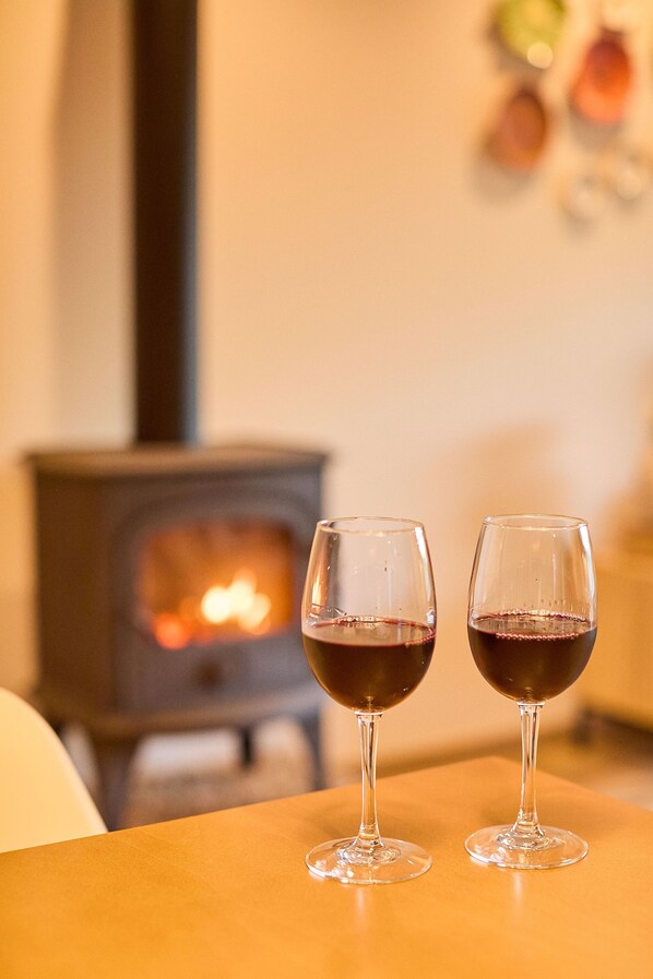 Two wine glasses on a table with a wood-burning stove in the background. - Villas Carreiro - Villa Musgo | Vineyard Escape with Private Pool, Porto (Maureles)
