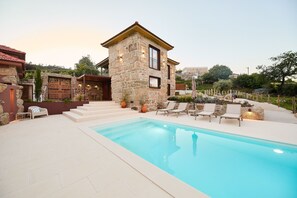 Un edificio de piedra con piscina y zona de estar exterior.