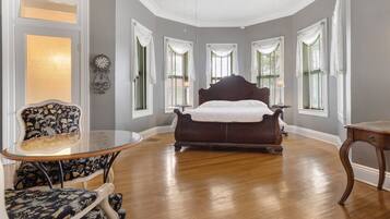 A bedroom with a large bed, a round table, and two chairs.