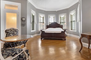 A bedroom with a large bed, a round table, and two chairs.