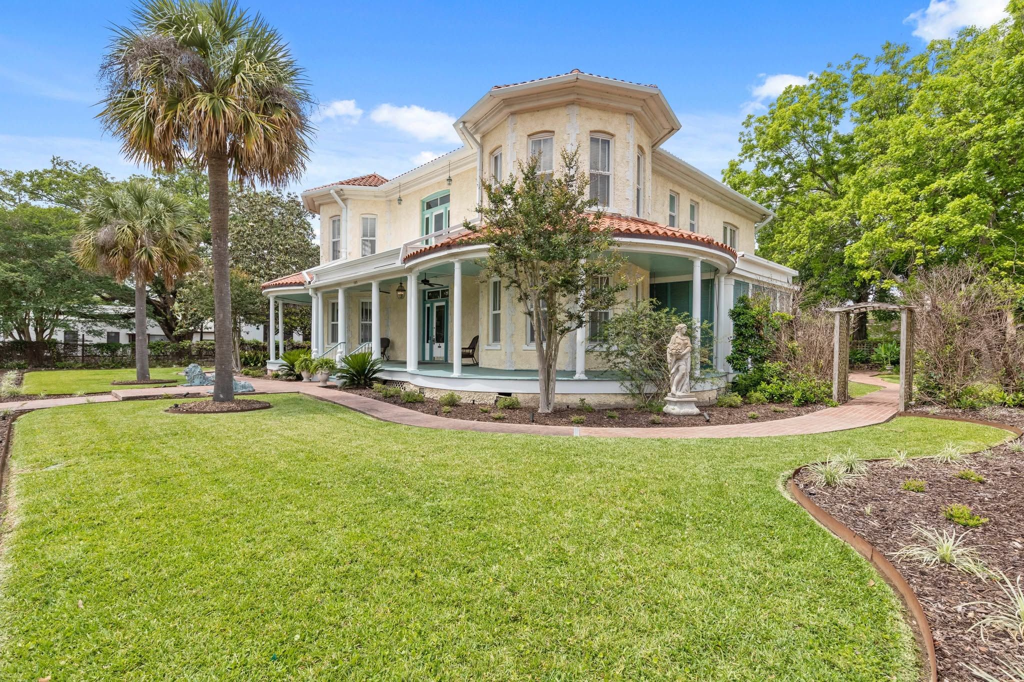 A two-story house with a wrap-around porch, a well-maintained lawn, and mature trees.