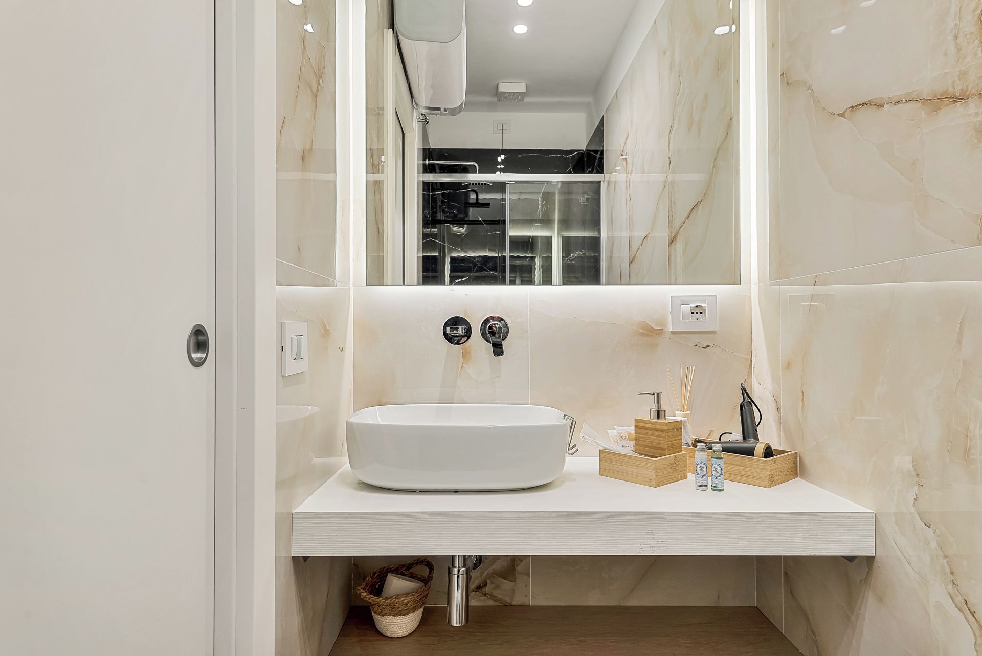 Een moderne badkamer met een witte wastafel, een rond wasbakje en een spiegel.