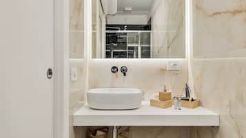 Een moderne badkamer met een witte wastafel, een rond wasbakje en een spiegel.