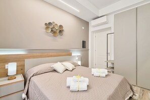 A hotel room with a bed, bedside table, wall decor, and a wardrobe.