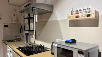 Una cocina con estufa a gas, microondas, especias en un organizador y dispensador de agua.