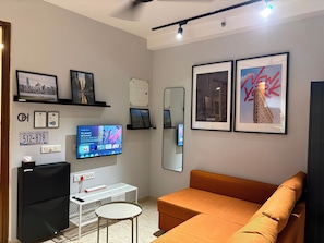 Un salon moderne avec un téléviseur à écran plat, un canapé et des tableaux encadrés accrochés au mur.