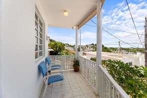 A balcony with white railings, a tiled floor, and a row of blue chairs. - Casa Pueblo Mar: Rincón Town Living with Sunset Sea Views (Rincon)