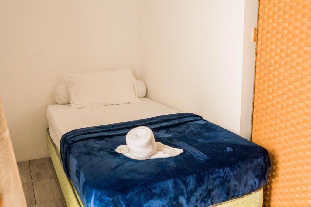 Ein kleines Bett mit einem weißen Kopfkissen und einer blauen Decke.