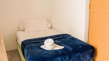 Ein kleines Bett mit einem weißen Kopfkissen und einer blauen Decke.