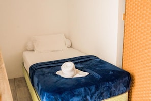 A small bed with a white pillow and a blue blanket. - Long Beach Laamu (Gan)
