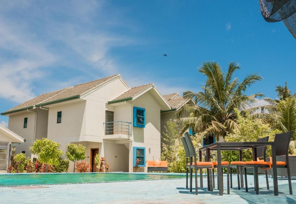 A two-story building with a swimming pool, outdoor seating, and palm trees.