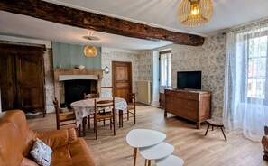 Uma sala de estar com lareira, móveis de madeira, televisão e área de jantar.