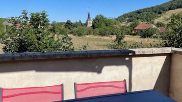 Eine Terrasse mit Tisch und Stühlen mit Blick auf eine ländliche Landschaft mit Kirche und Häusern.