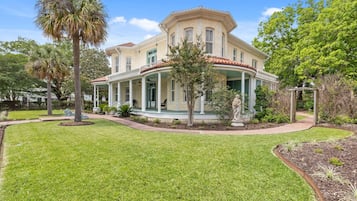 A two-story house with a wrap-around porch, a well-maintained lawn, and mature trees.