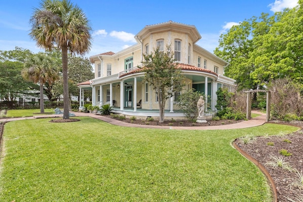 A two-story house with a wrap-around porch, a well-maintained lawn, and mature trees.