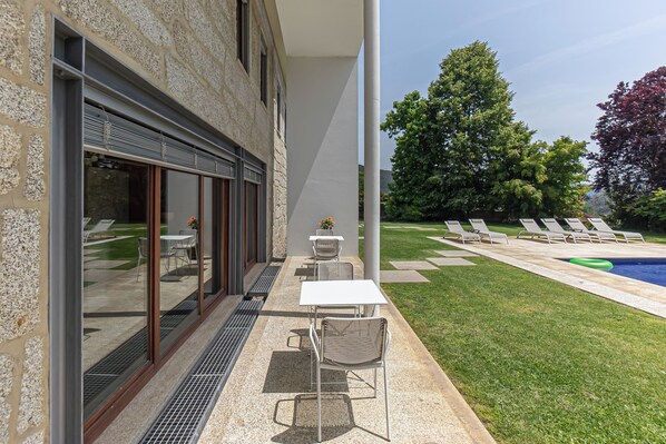 Un pati exterior modern amb piscina, gandules i zona de menjador amb taules i cadires.